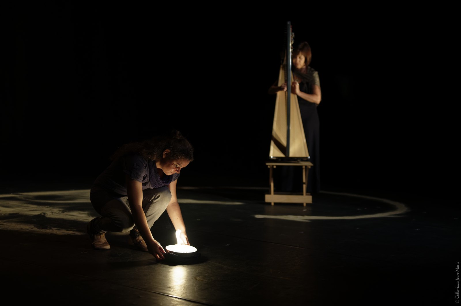 Eglantine Jouve accroupie pose une lumière au sol, Elisa Vellia à la harpe en fond