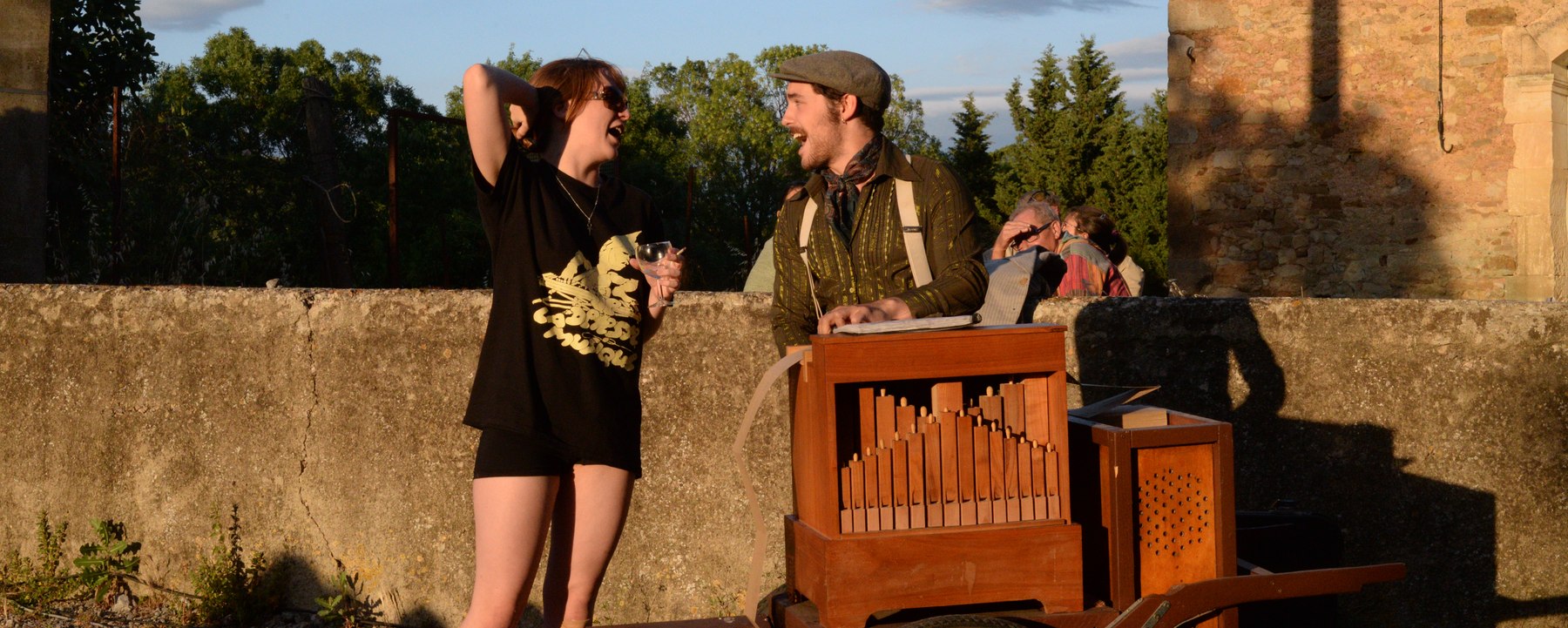 Aymé Médeville tourne la manivelle de son orgue de Barbarie devant des tablées de village