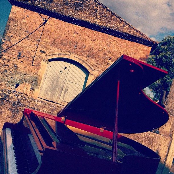 Le piano rouge installé dehors, devant un ouvrage de pierre